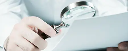 Eine Hand hält eine Lupe über ein Dokument